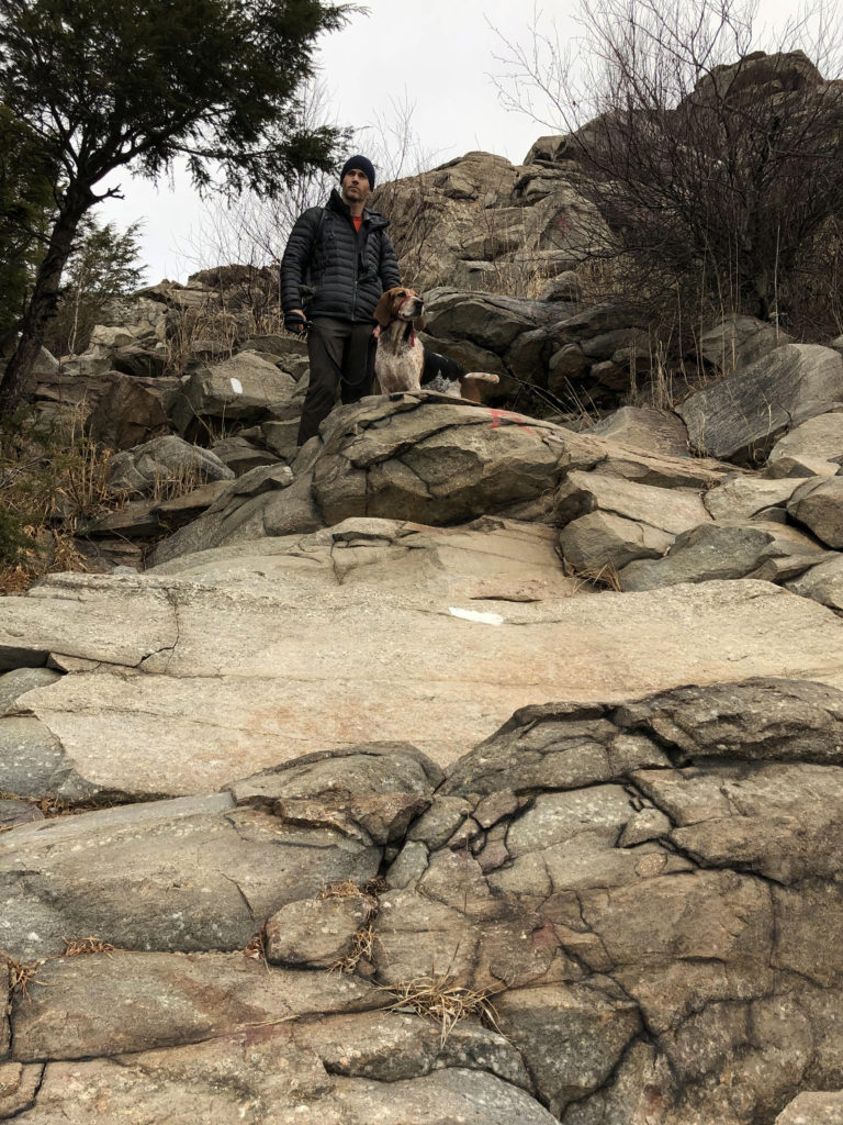 man and dog reach top of rocks