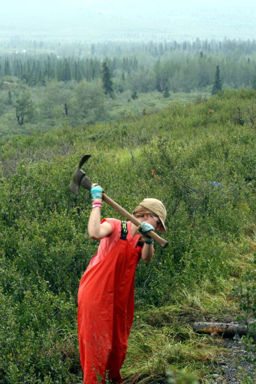 Girl swings pulaski during trail maintenance in Denali National Park, Alaska