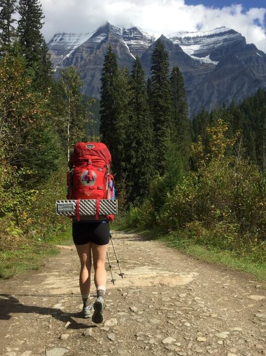 woman backpacking in front of mountain range
